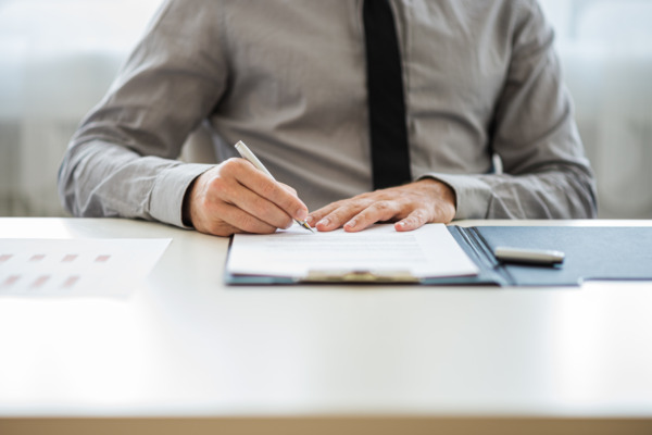 Businessman or lawyer sitting at his desk signing a document or contract to do with estate planning.