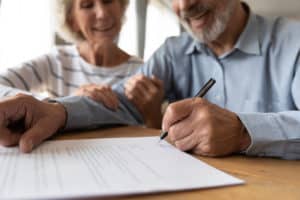 making a well. two people review a document on a desk. the man is holding a men as if he is about to sign.