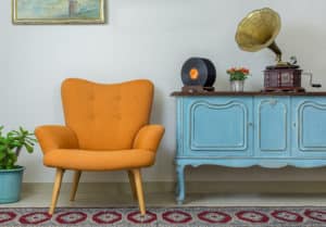valuing assets in an estate - Vintage interior of retro orange armchair, vintage wooden light blue sideboard, old phonograph (gramophone), vinyl records on background of beige wall, tiled porcelain floor, and red carpet in the article valuing assets for an estate part two