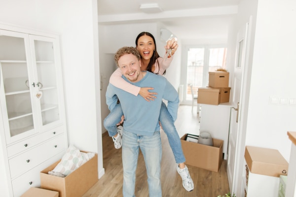 man give his partner a piggy back as she holds up the keys celebrating buying a house in Scotland