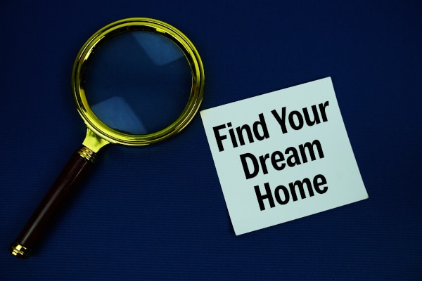 Magnifyig glass about to focus on a postig saying "Find your Dream Home" on a dark blue background