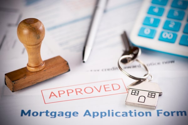 Mortgage application form with Approved stamped in red over it with a stamp, keys and a calculator sitting on top