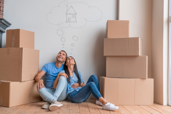 Couple thinking of their dream house with boxes piled beside them and a title with a survivorship destination in Scotland