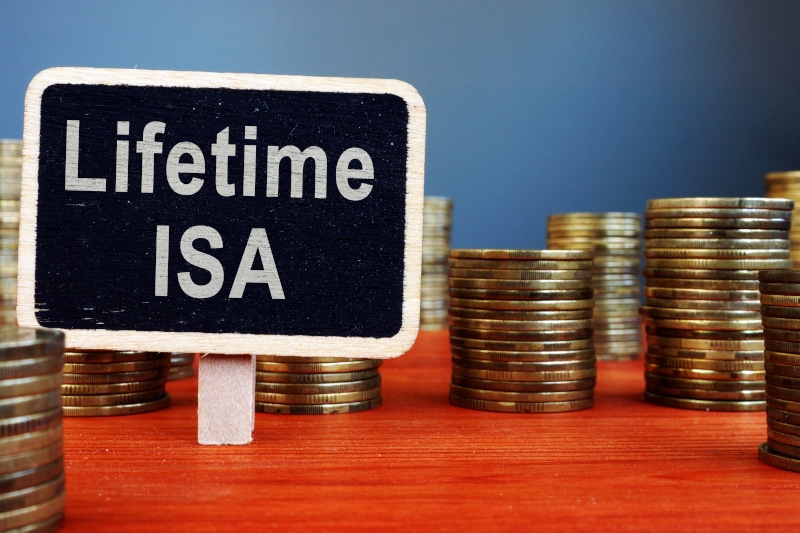 Coins stacked on a red topped table with a sign sticking up from it saying "Lifetime ISA" Scotland