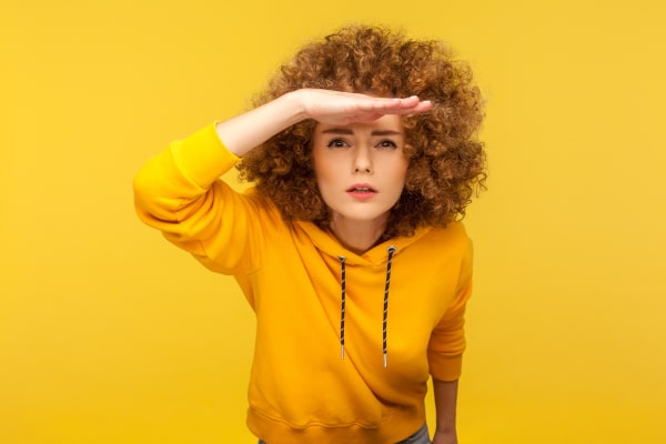 Woman with her hand above her eyes looking for another interest rate cut on the horizon