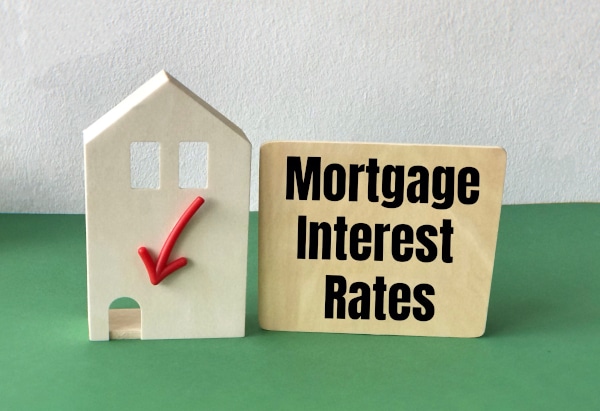 Model house with a red down arrow on the front with a sign beside is saying "Mortgage Interest Rates" as a resutl of interest rate cut Scotland property market
