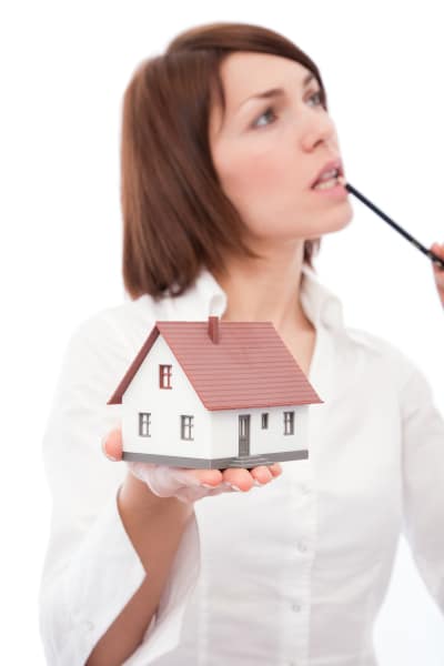 Famale property buyer with a model house in her hand sucking on a pencil as she contemplates the Home Report in Scotland