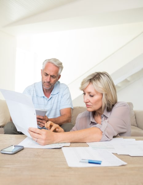 Older couple sitting together at a table reading and discussing a Will document.