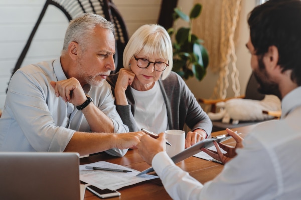 Solicitor explaining a Will to older clients across a desk in a professional office.